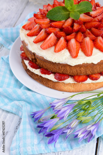 Delicious biscuit cake with strawberries on table close-up