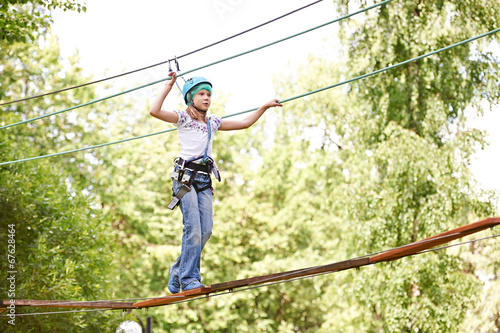 Girl is climbing to high rope bridge