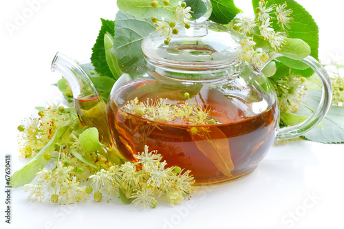 Teapot with linden tea and flowers on white background photo