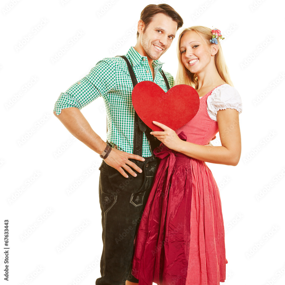 Paar mit Dirndl und Lederhose hält Herz Paar mit Dirndl und Lederhose hält Herz