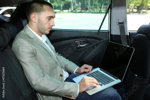 Man sitting in car with laptop © Africa Studio