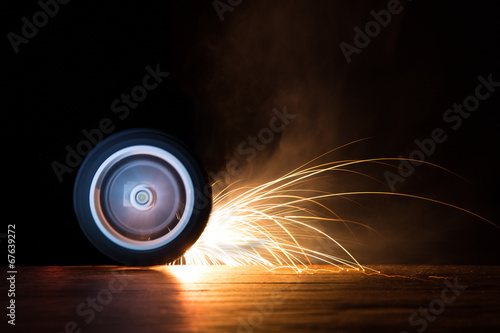 Toy wheel spinning on black background with sparks flying