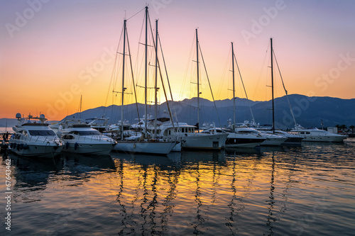 Sailing boats in marina at sunset.
