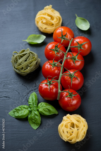 Branch of red tomatoes, raw colored tagliatelle and green basil