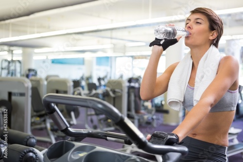 Fit woman taking a drink on the exercise bike