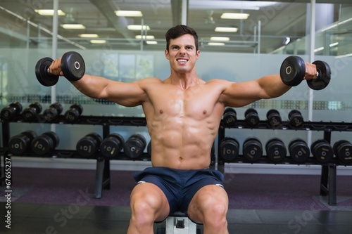 Fototapeta Naklejka Na Ścianę i Meble -  Muscular man exercising with dumbbells in gym
