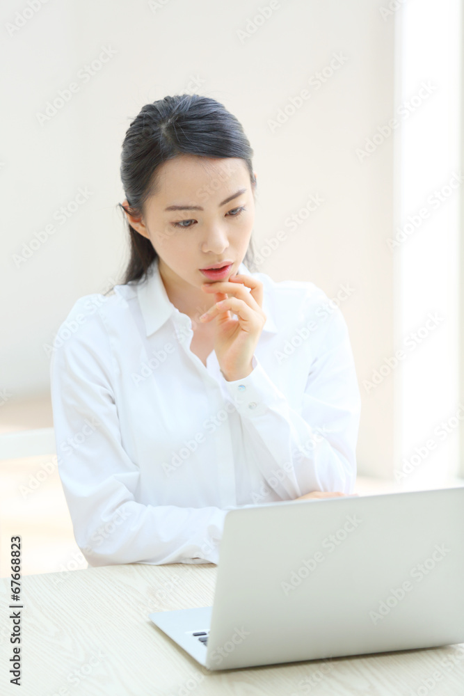 ノートパソコンの前で悩む若い女性 ノートパソコンの前で悩む若い女性