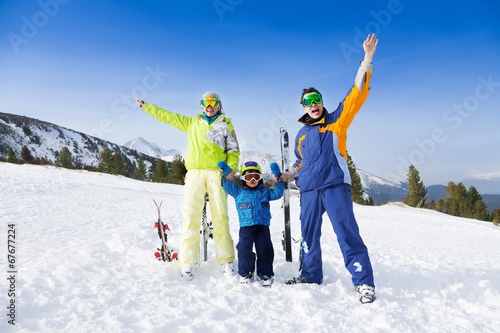 Happy parents in ski masks hold hands of son