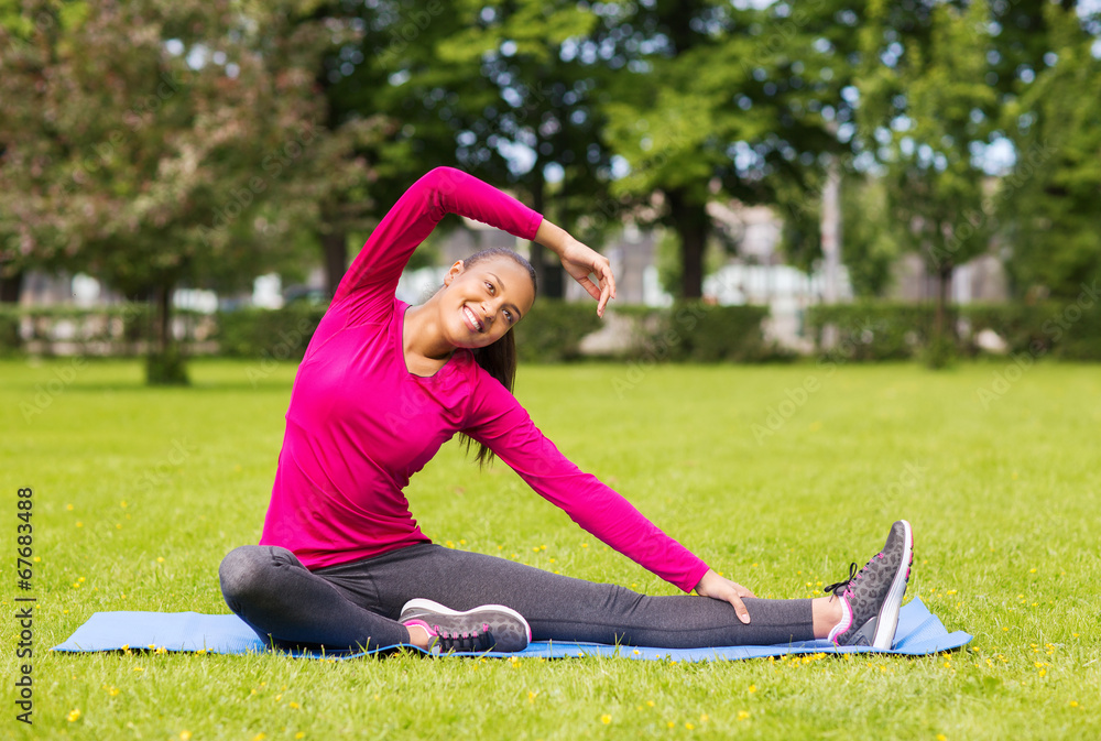 smiling woman stretching leg on mat outdoors smiling woman stretching leg on mat outdoors