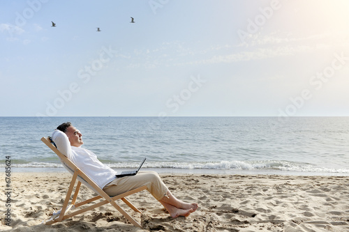 Obraz na płótnie man with laptop computer relaxing on the beach w salonie
