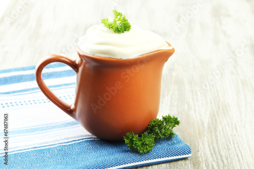 Sour cream in pitcher on table close-up