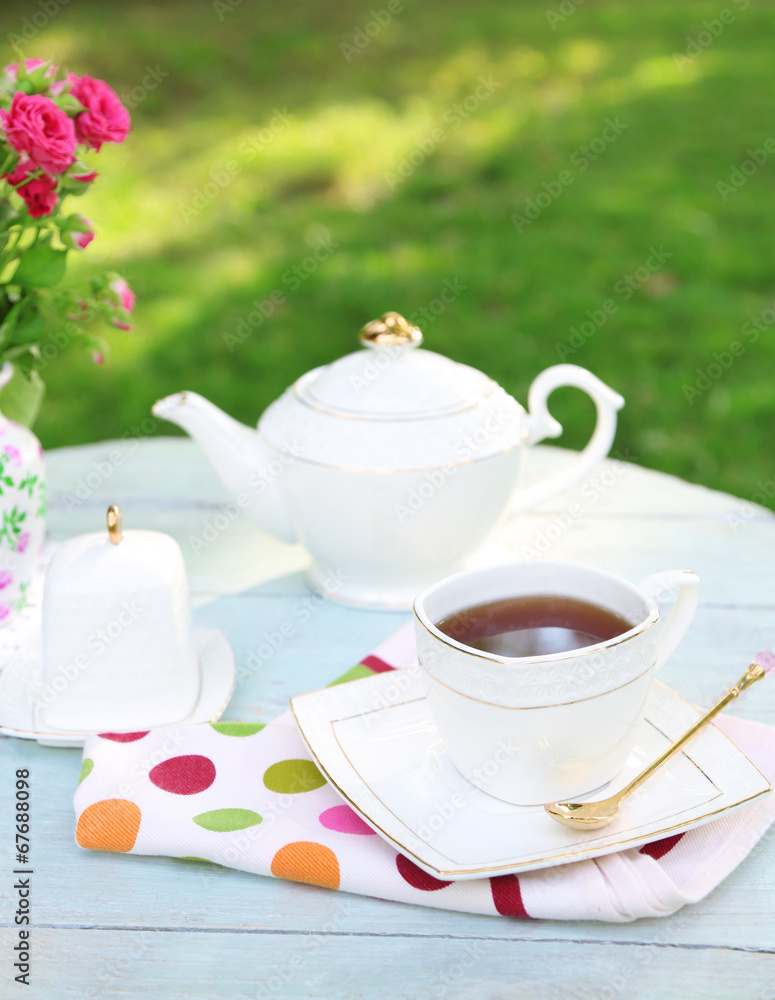 Fototapeta premium Teapot and cup on table, close-up, in garden