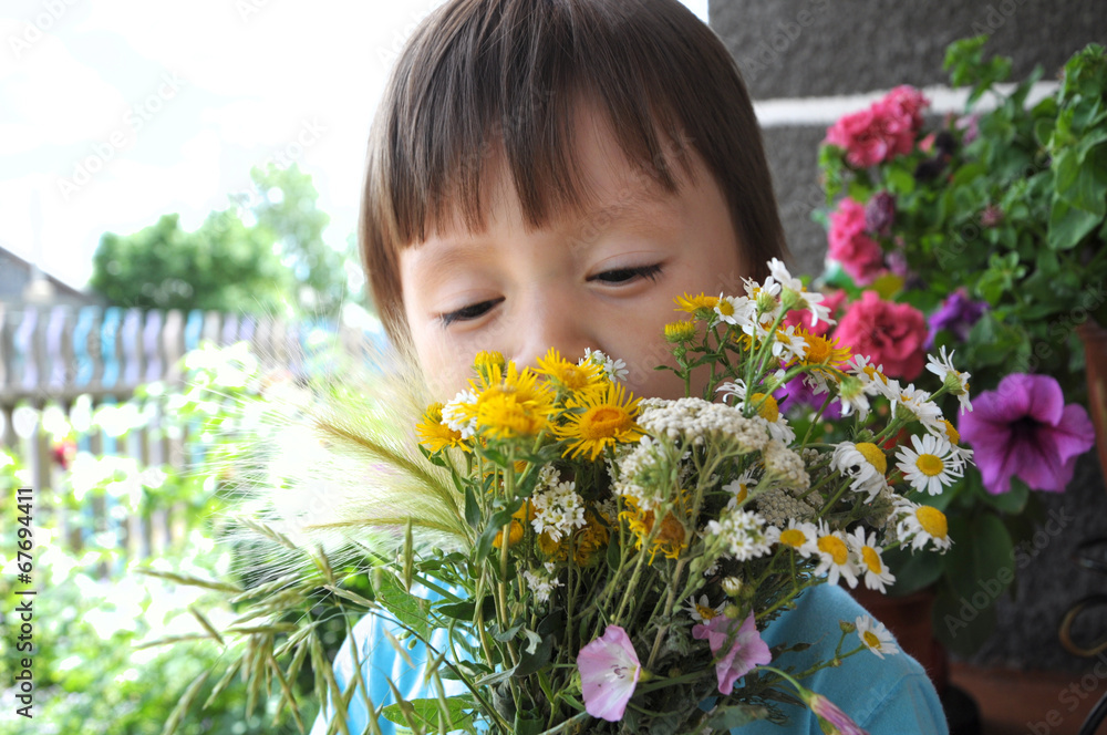 Boy smelling summer bouquet of wildflowers Boy smelling summer bouquet of wildflowers
