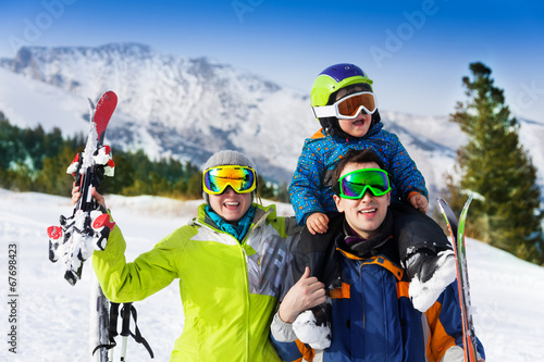 Parents and child on dad's shoulders in ski masks