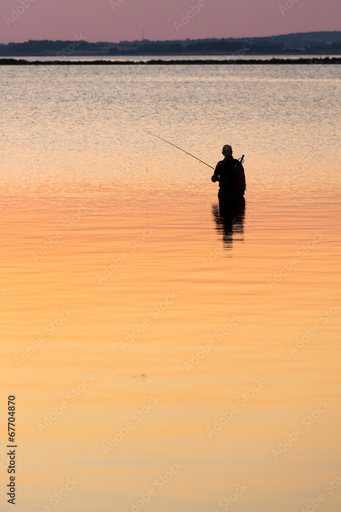 Man standing in water fishing