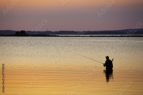 Man standing in water fishing