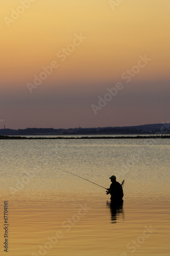 Man standing in water fishing