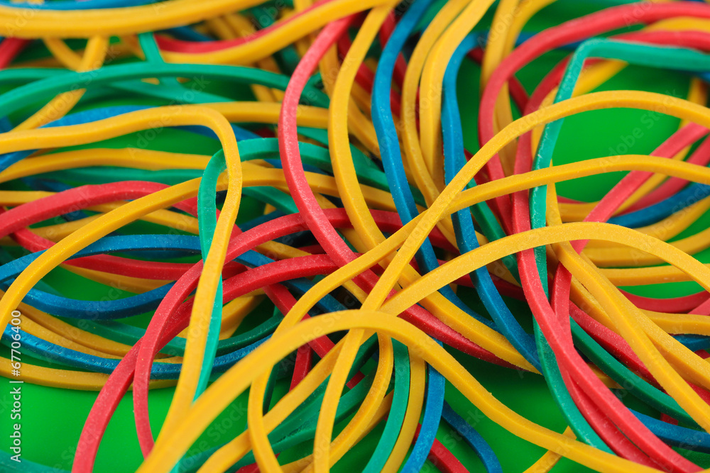 Colorful rubber bands on green background close-up