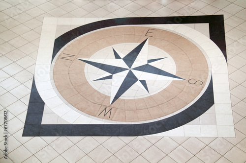 Large compass inlaid with black and light brown tiles on floor