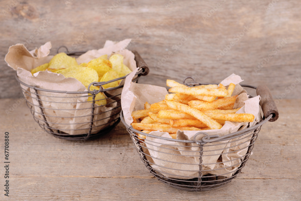Tasty french fries in metal basket and potato chips