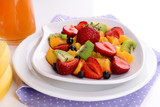 Fresh fruits salad on plate on napkin close up