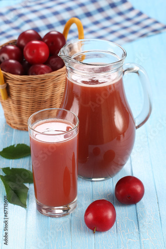 plum juice in a glass and pitcher, plums in a wicker basket