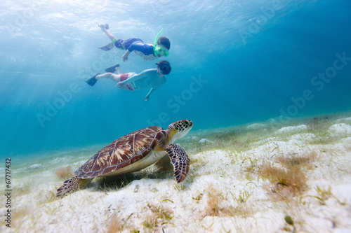 Family snorkeling with sea turtle