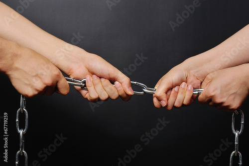 鎖を引き合う二人の人間の手