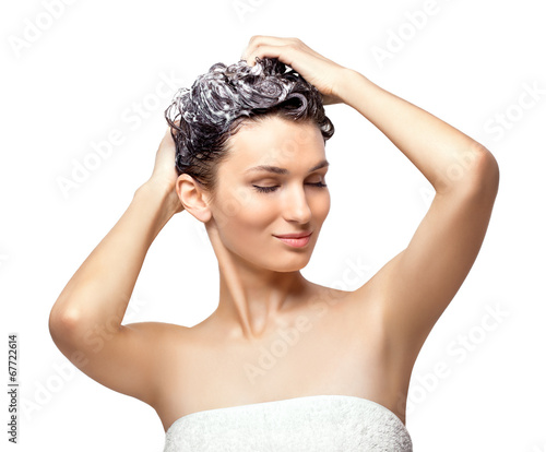 Beautiful young woman soaping her head, isolated on white