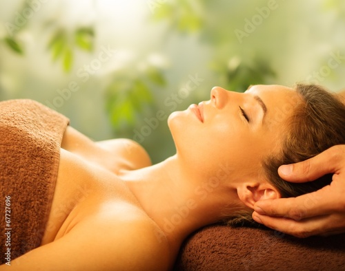 Young woman having face massage in a spa salon