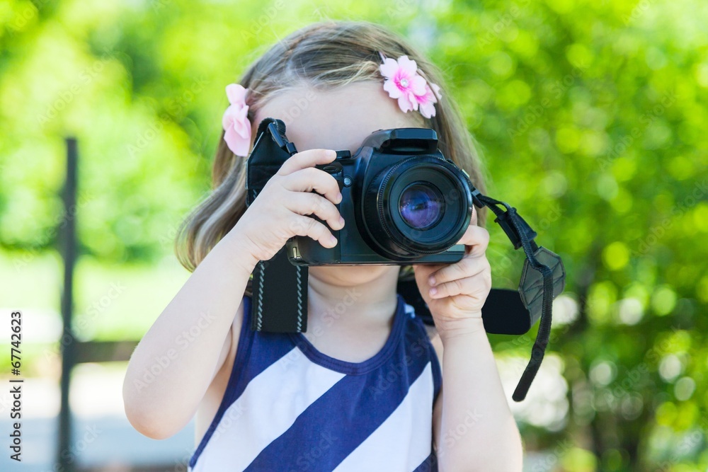 Little girl who takes pictures with a photo camera in park