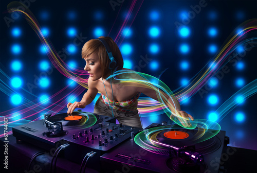 Young Dj girl mixing records with colorful lights photo