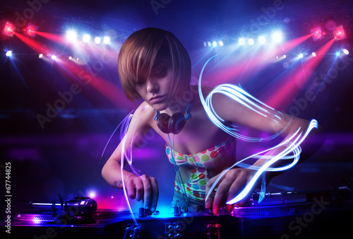 Disc jockey girl playing music with light beam effects on stage © ra2 studio