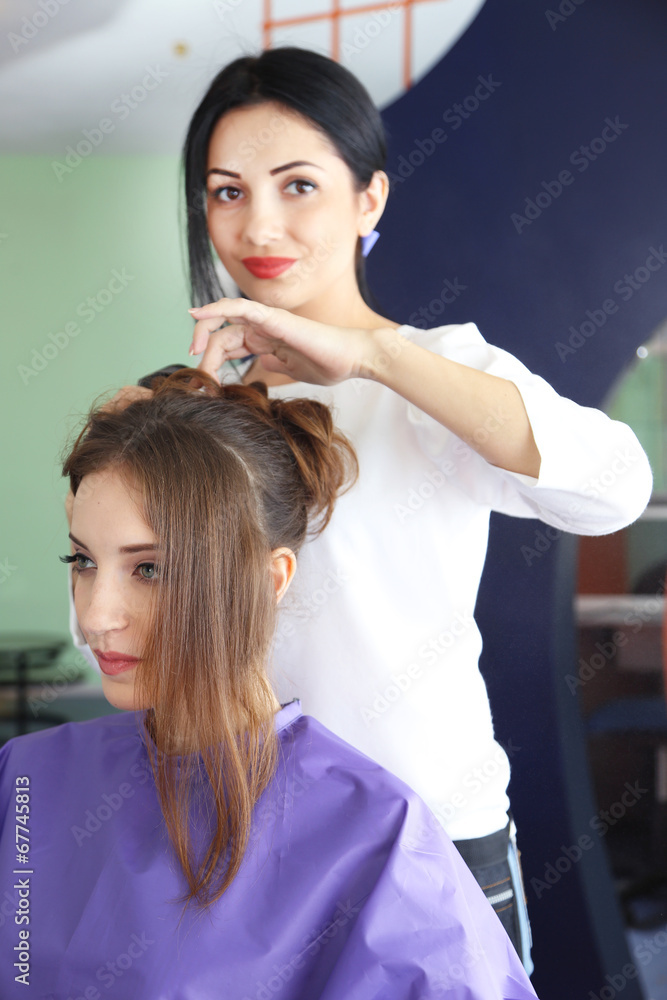 Fototapeta premium Young woman hairdresser do hairstyle girl in beauty salon