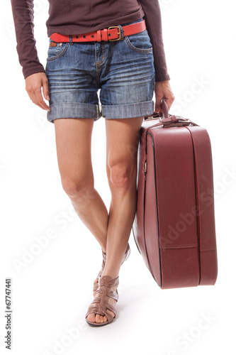 female legs in shorts and suitcase in hand