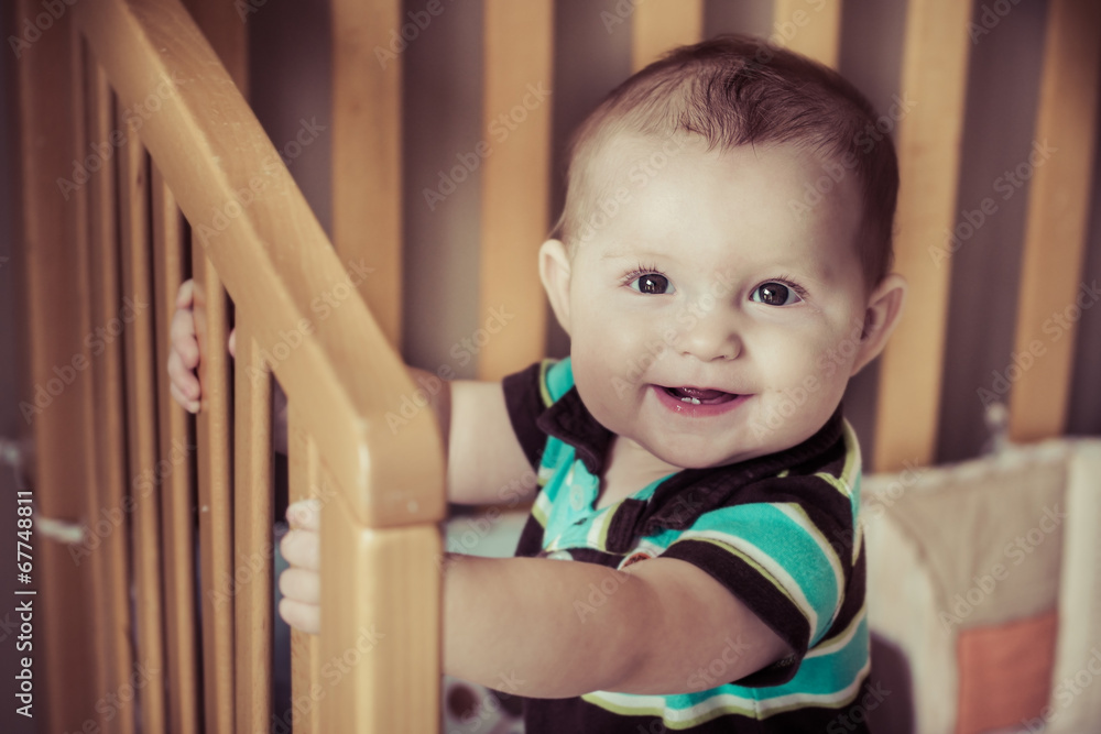 Happy baby standing up in his crib in filtered