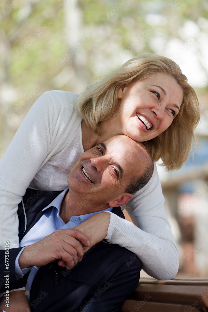 Mature family couple staying outdoor at fall day and smiling