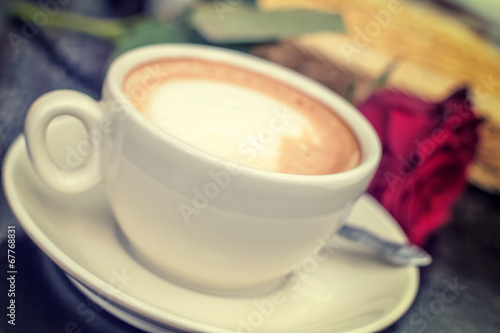 Blurred white cup of coffee with rose