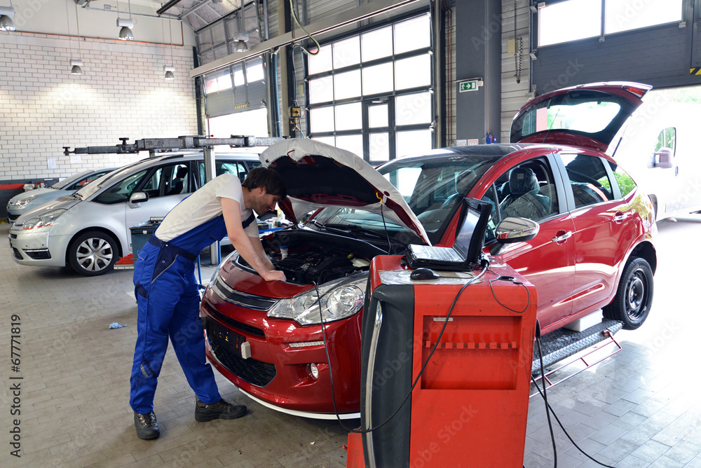 Obraz premium KFZ Mechaniker prüft Motor // mechanic in car workshop