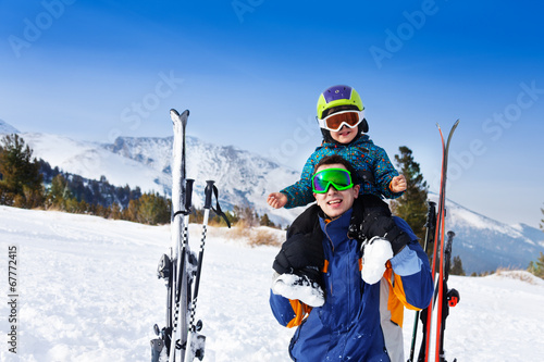 Happy father in ski mask with son on shoulders
