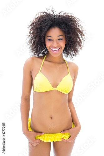 Slim girl in yellow bikini smiling at camera