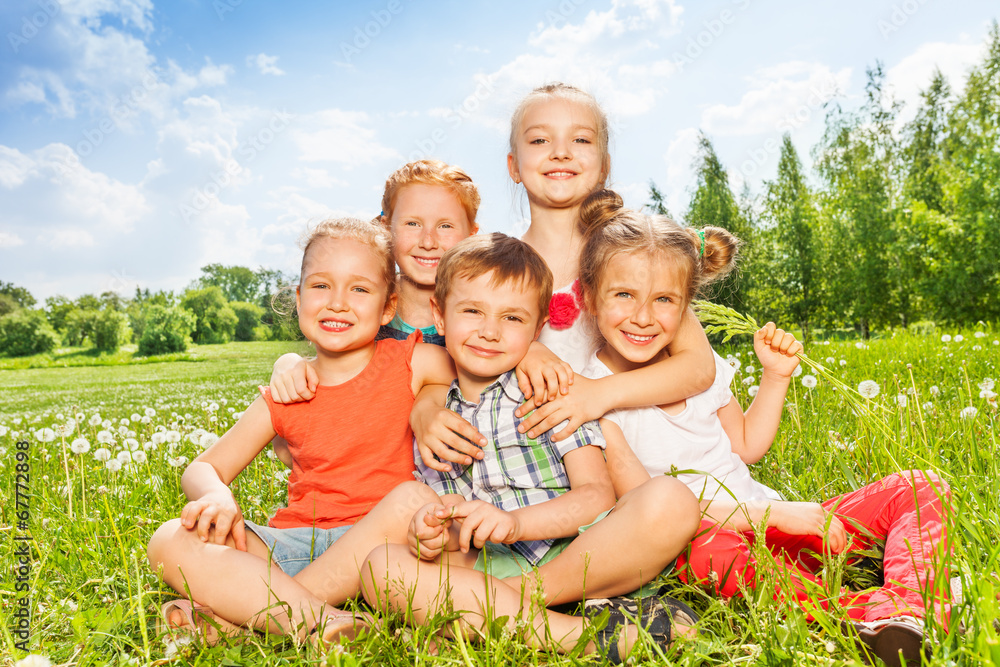 Fototapeta premium Five wonderful kids sitting together on a meadow