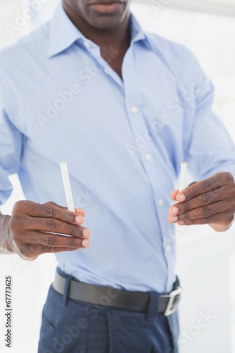 Businessman deciding between electronic or normal cigarette