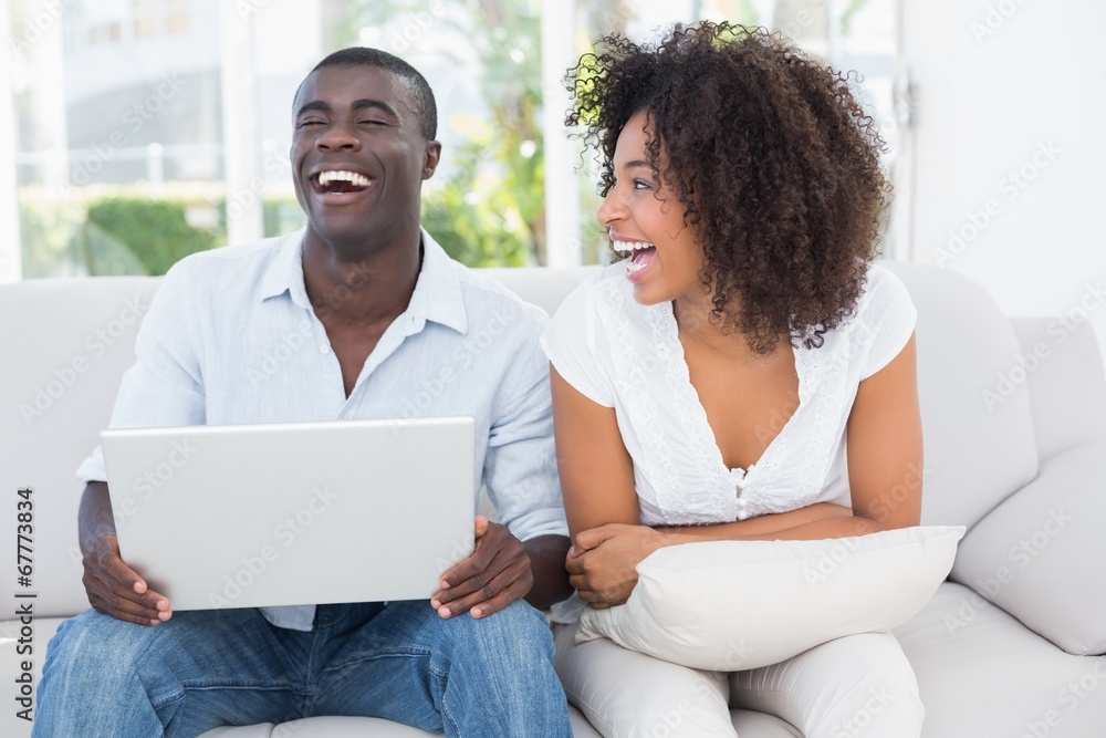 Attractive couple using laptop together on sofa Attractive couple using laptop together on sofa