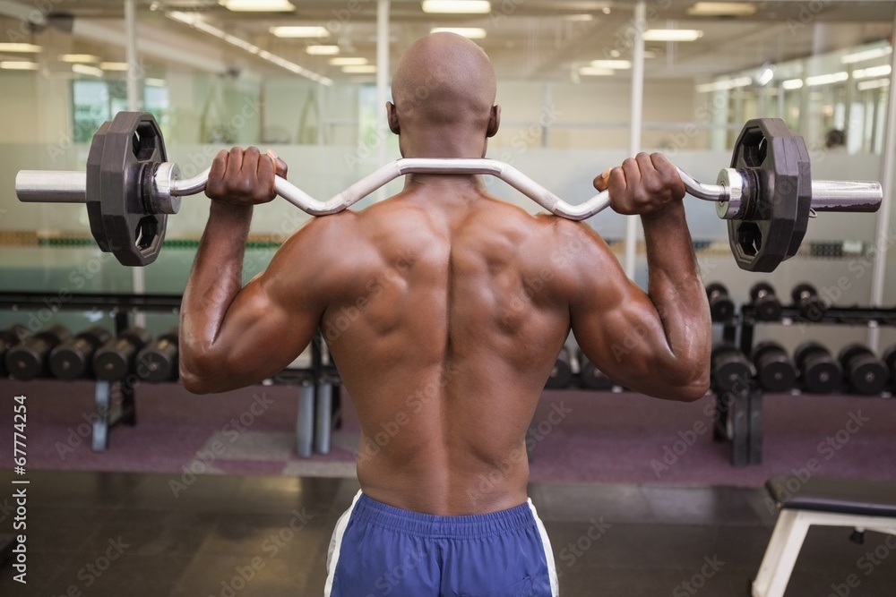 Muscular man lifting barbell in gym Muscular man lifting barbell in gym