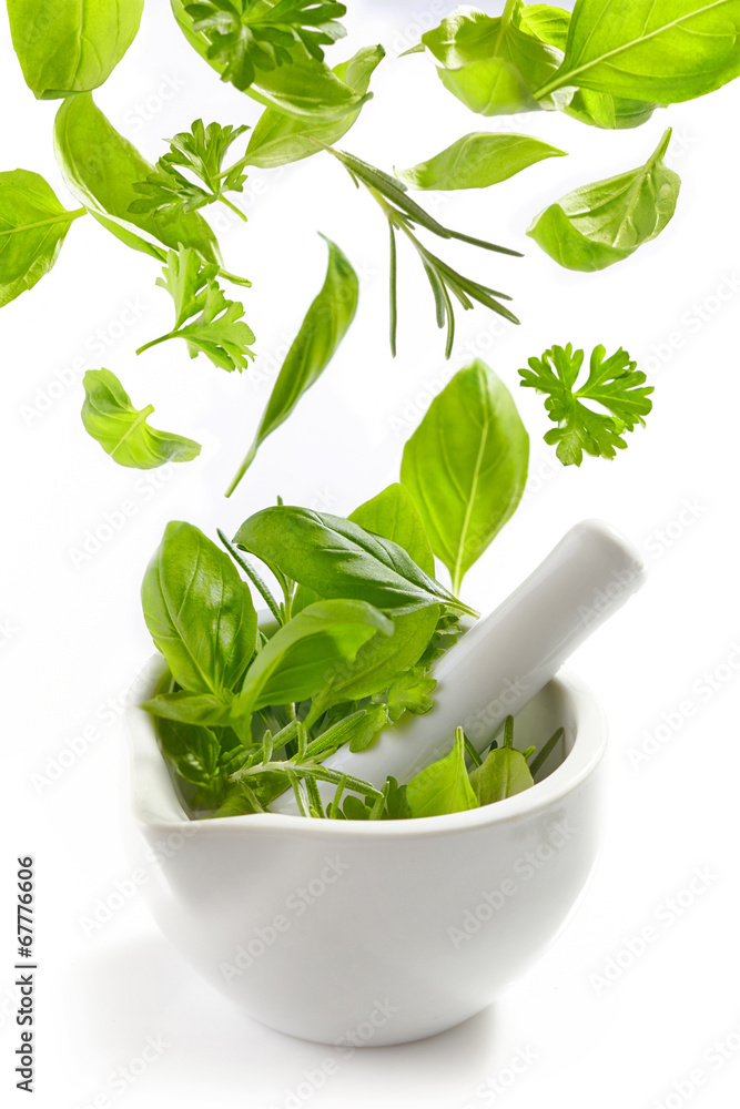green herbs falling into mortar and pestle