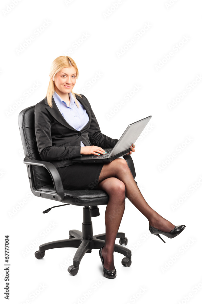 Businesswoman working on laptop seated on chair Businesswoman working on laptop seated on chair