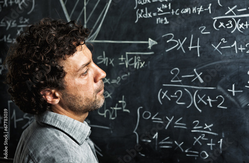  portrait of caucasian teacher with curly hair. slate blackboard on the background. school and teaching concept.