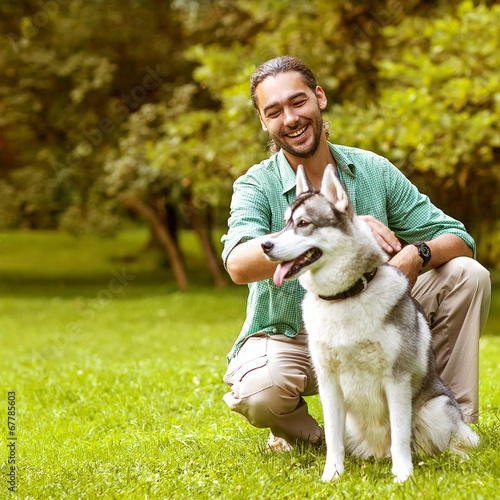 Man and Husky dog walk in the park. 