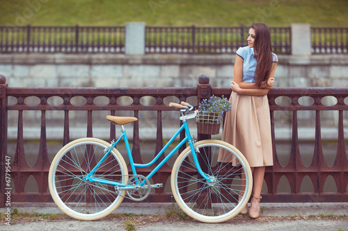 Young beautiful, elegantly dressed woman with bicycle, summer an